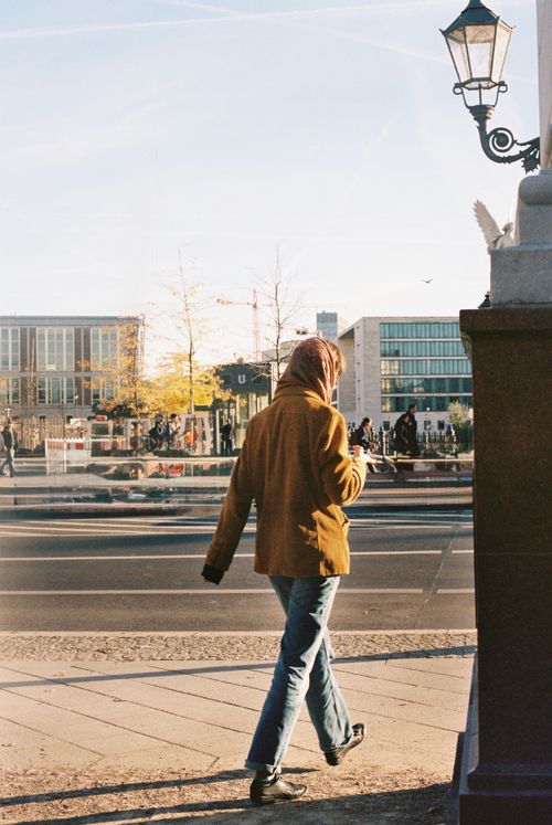 Free A person in a jacket walks through an urban street on a sunny autumn day. Stock Photo