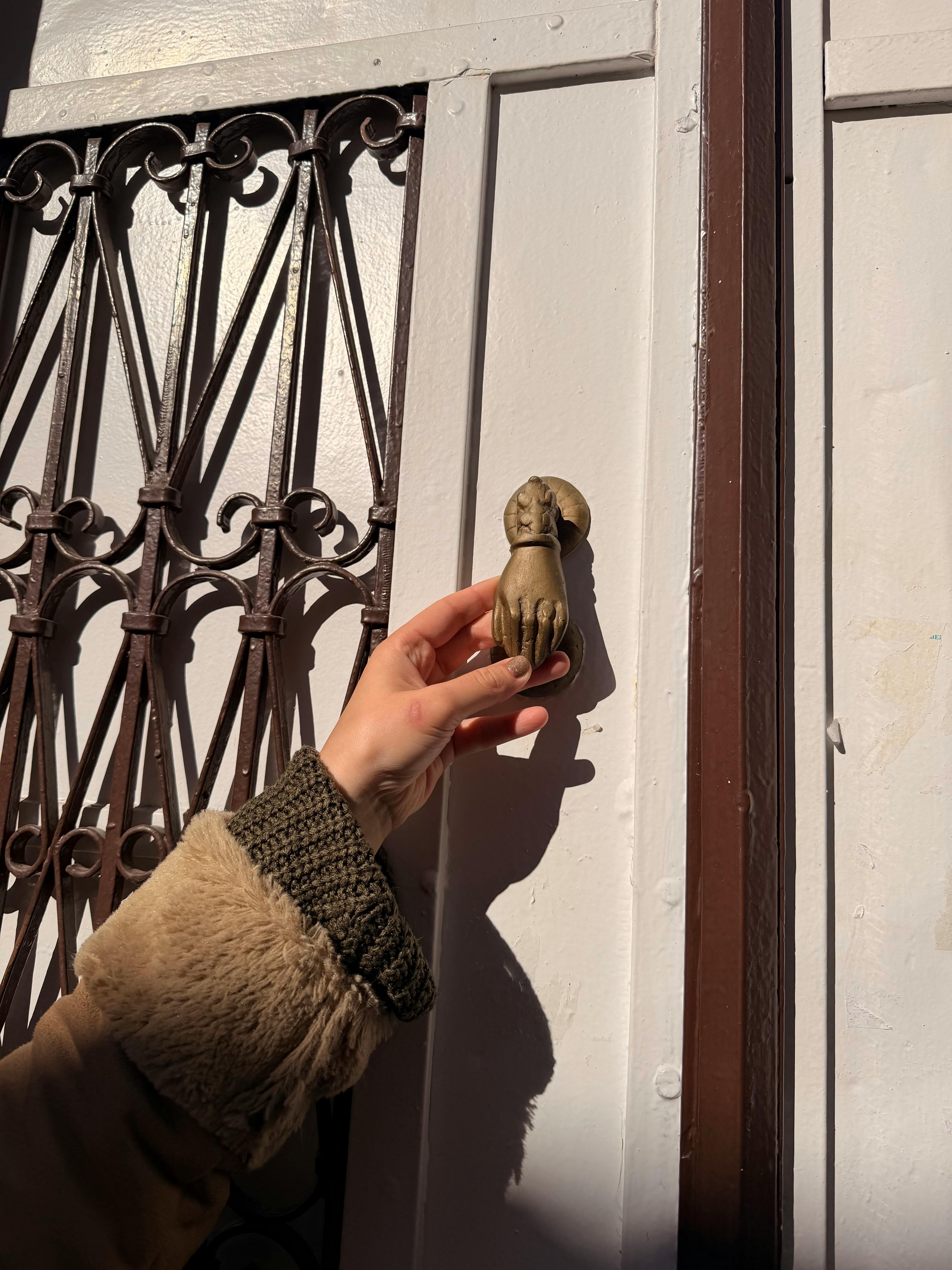 De franc Una mà busca un picaporta decoratiu de bronze en un dia assolellat. Foto d'estoc