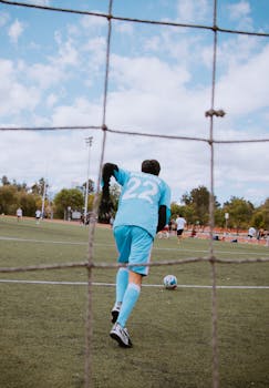 Rear view of a soccer player on a field, preparing to kick the ball during a match.