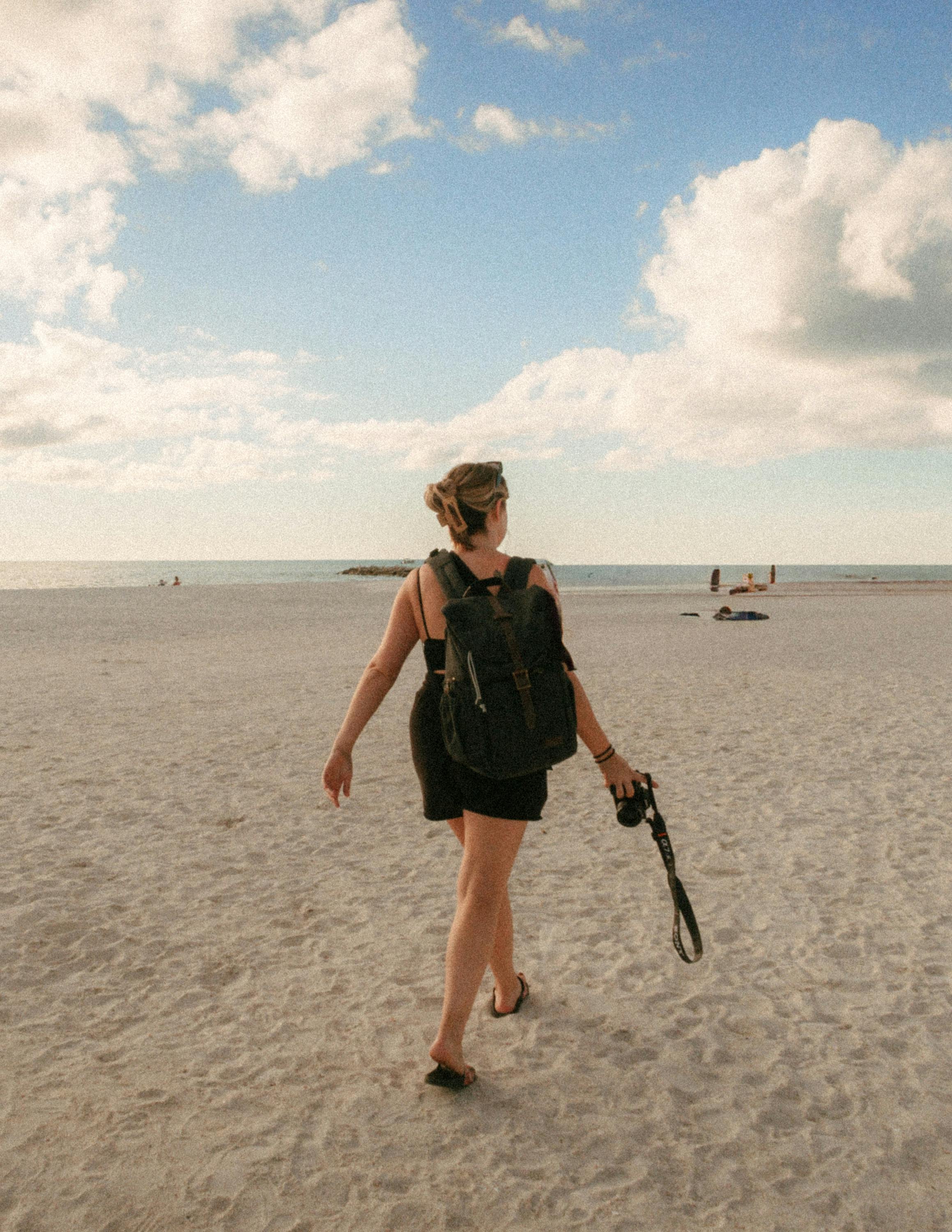 Travel creator walking on the beach with camera in hand