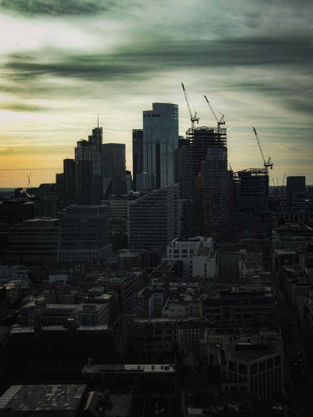 City skyline at dusk with tower cranes over active construction