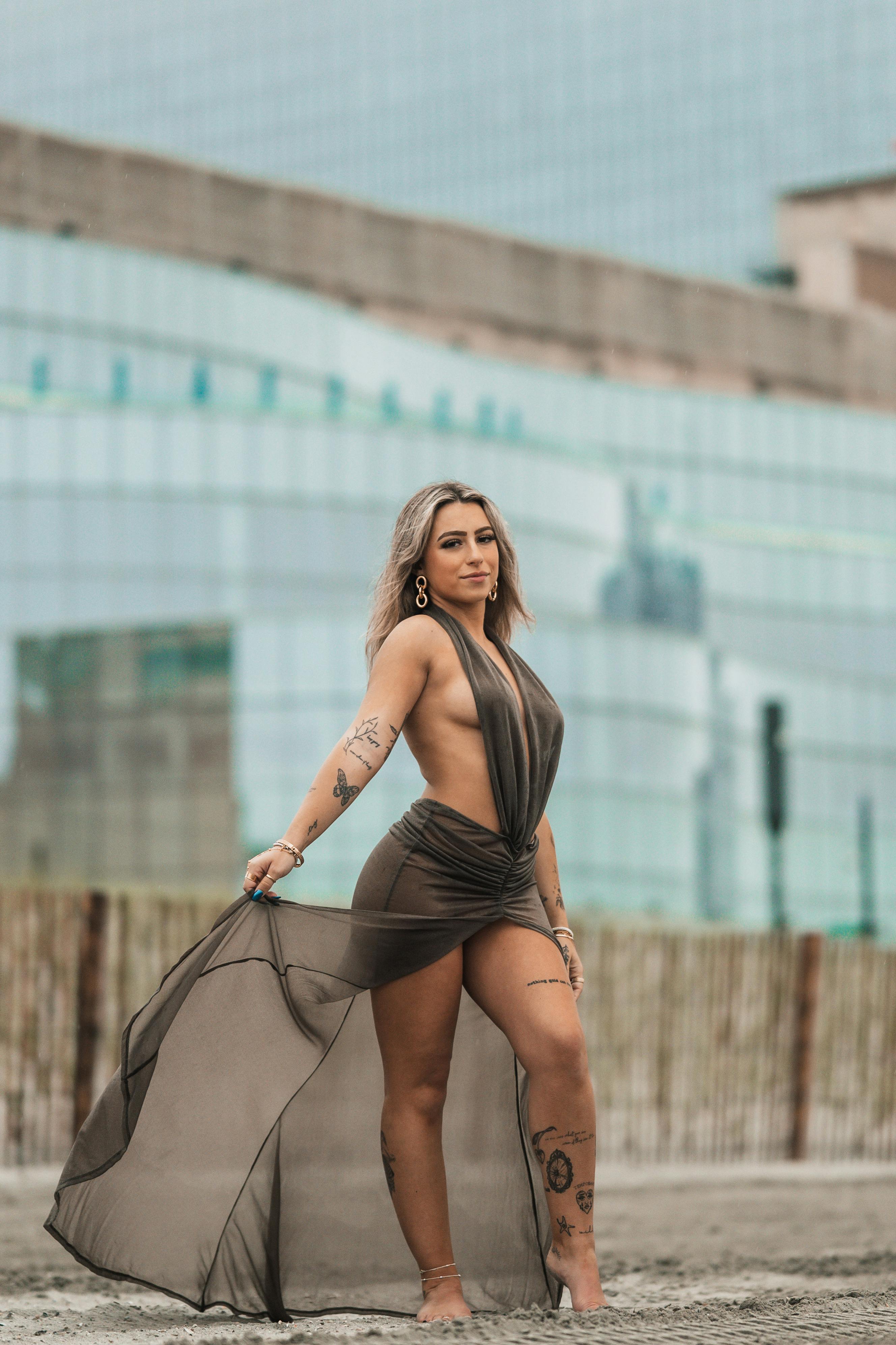 Gratis Stilig kvinne i moteriktig kjole poserer selvsikkert utendørs og viser frem moderne eleganse. Arkivbilde