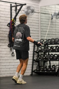 Active male exercising with jump rope in sleek gym setting, emphasizing fitness and health.