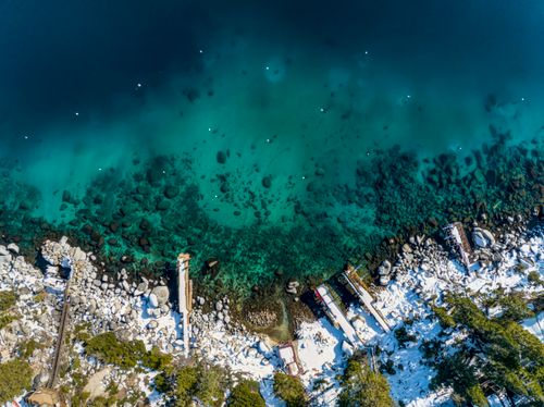 Free A stunning aerial shot of Lake Tahoe's turquoise waters and snowy shoreline, capturing winter's beauty. Stock Photo