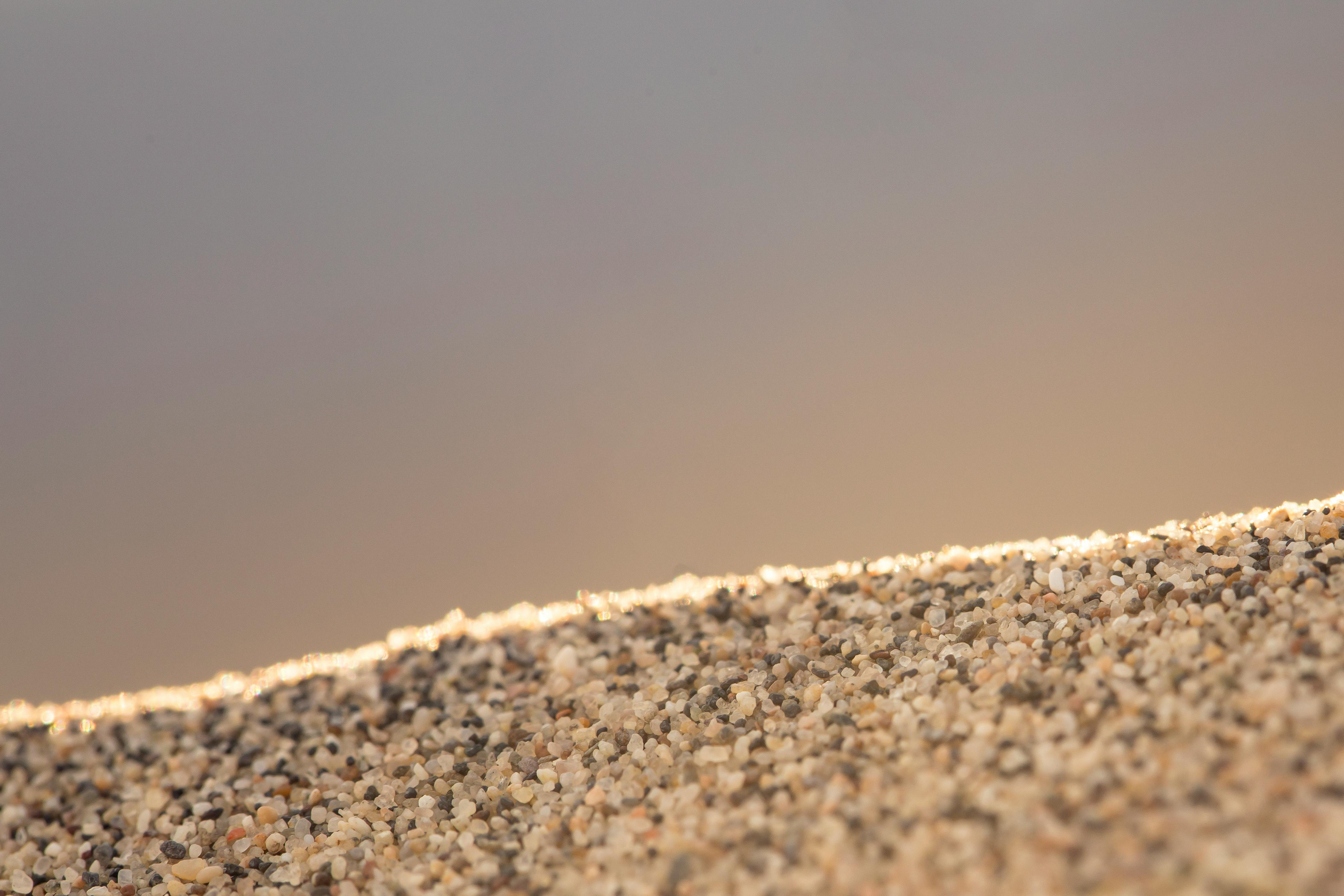Free Macro shot of sunlit sand grains on a beach, creating a warm, textured vista. Stock Photo