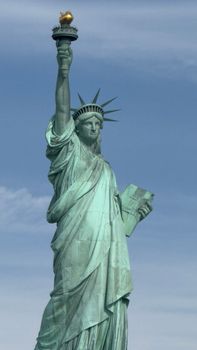 The Statue of Liberty stands majestically against a backdrop of blue sky, symbolizing freedom.