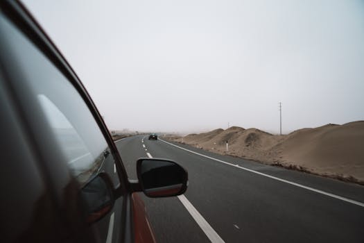 A car travels on a winding desert highway, showcasing a serene road trip atmosphere.