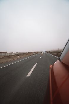 A scenic view of a deserted highway stretching through a barren desert landscape.