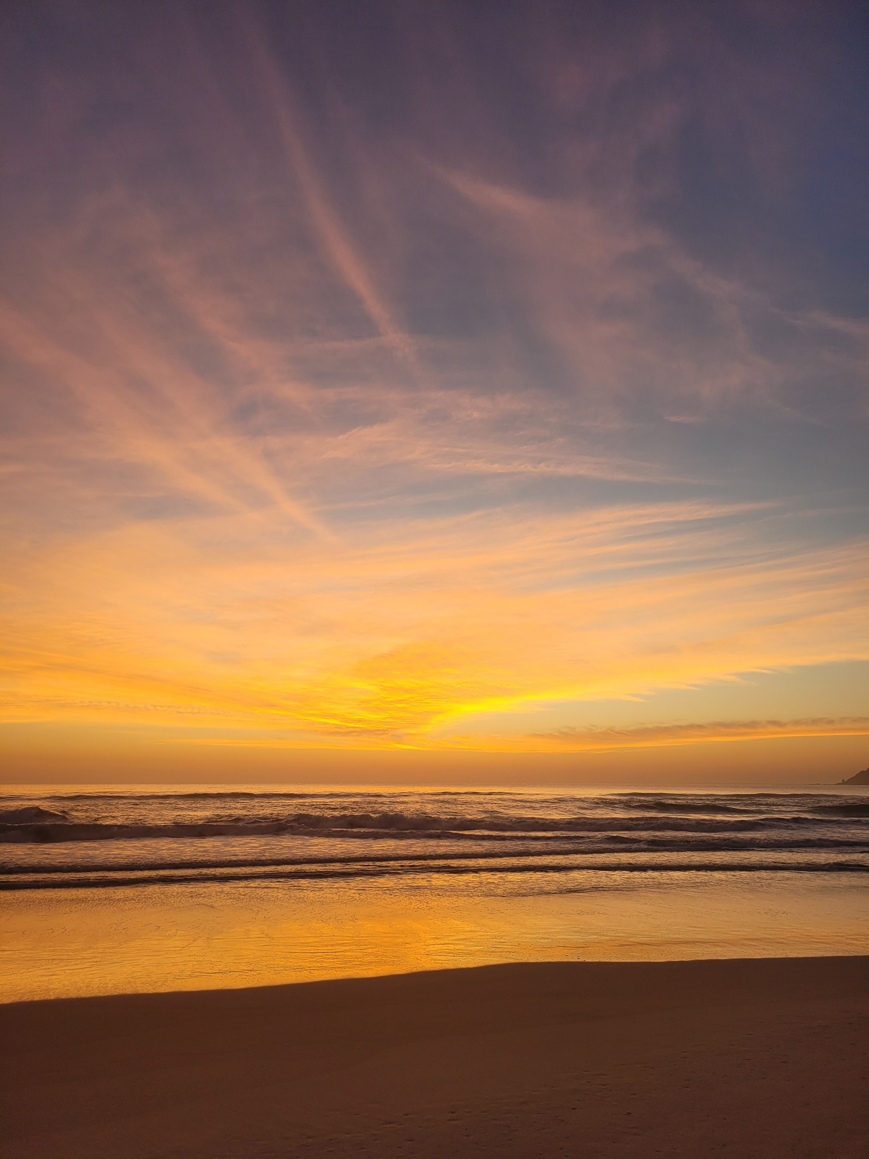 soft pastel sunrise over a calm ocean coastline