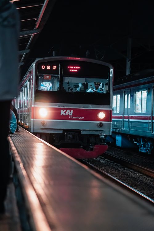 Free Commuter train arriving at Jakarta station at night, vibrant and cinematic scene. Stock Photo