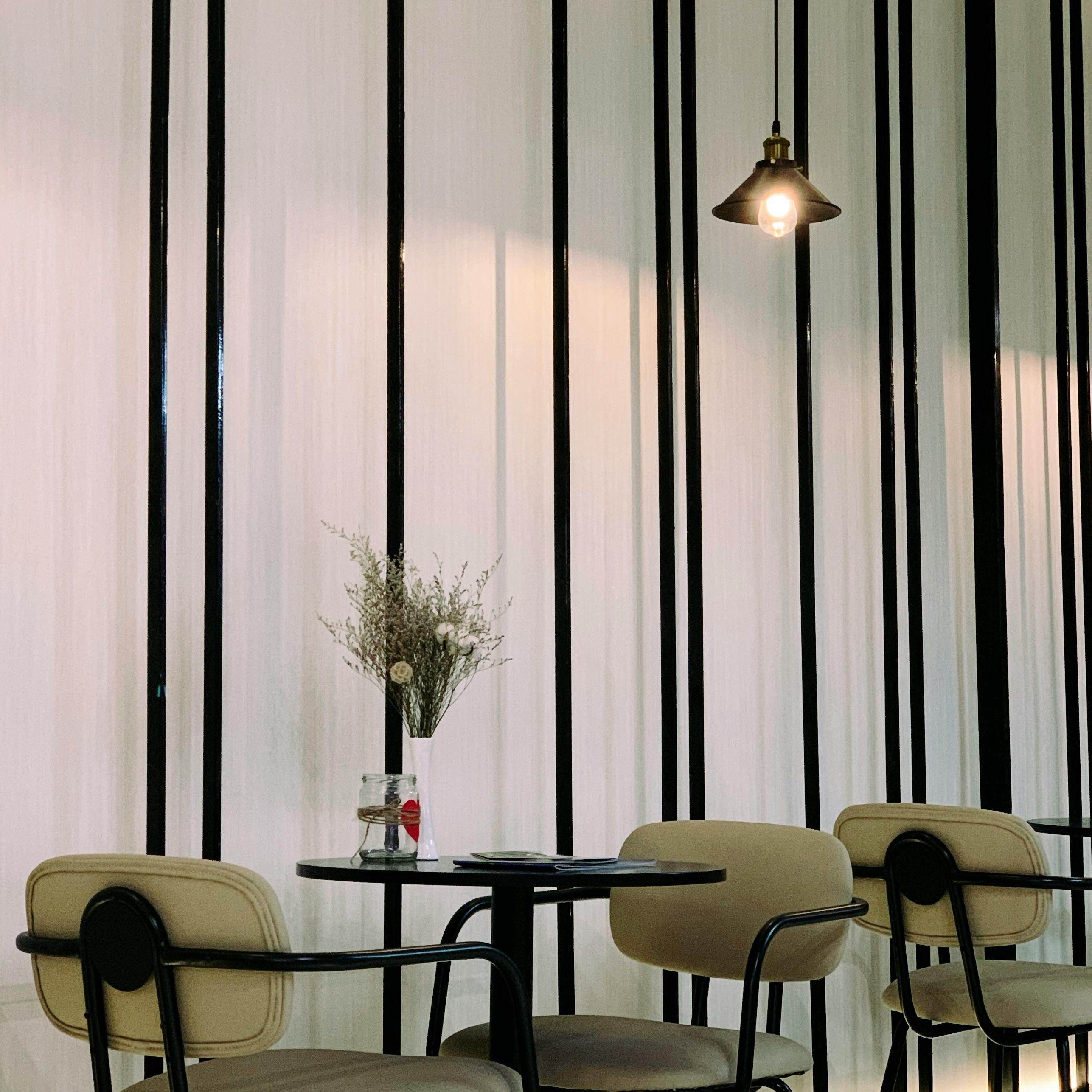 Kostenlos Stilvolles Café-Ambiente in Bến Tre, Vietnam, mit eleganten Stühlen, einer Vase mit Blumen und stimmungsvoller Beleuchtung. Stock-Foto