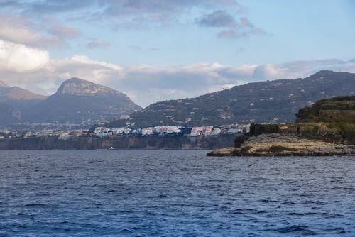 Free Picturesque coastal view of an Italian village on a hill, surrounded by the Mediterranean Sea. Stock Photo