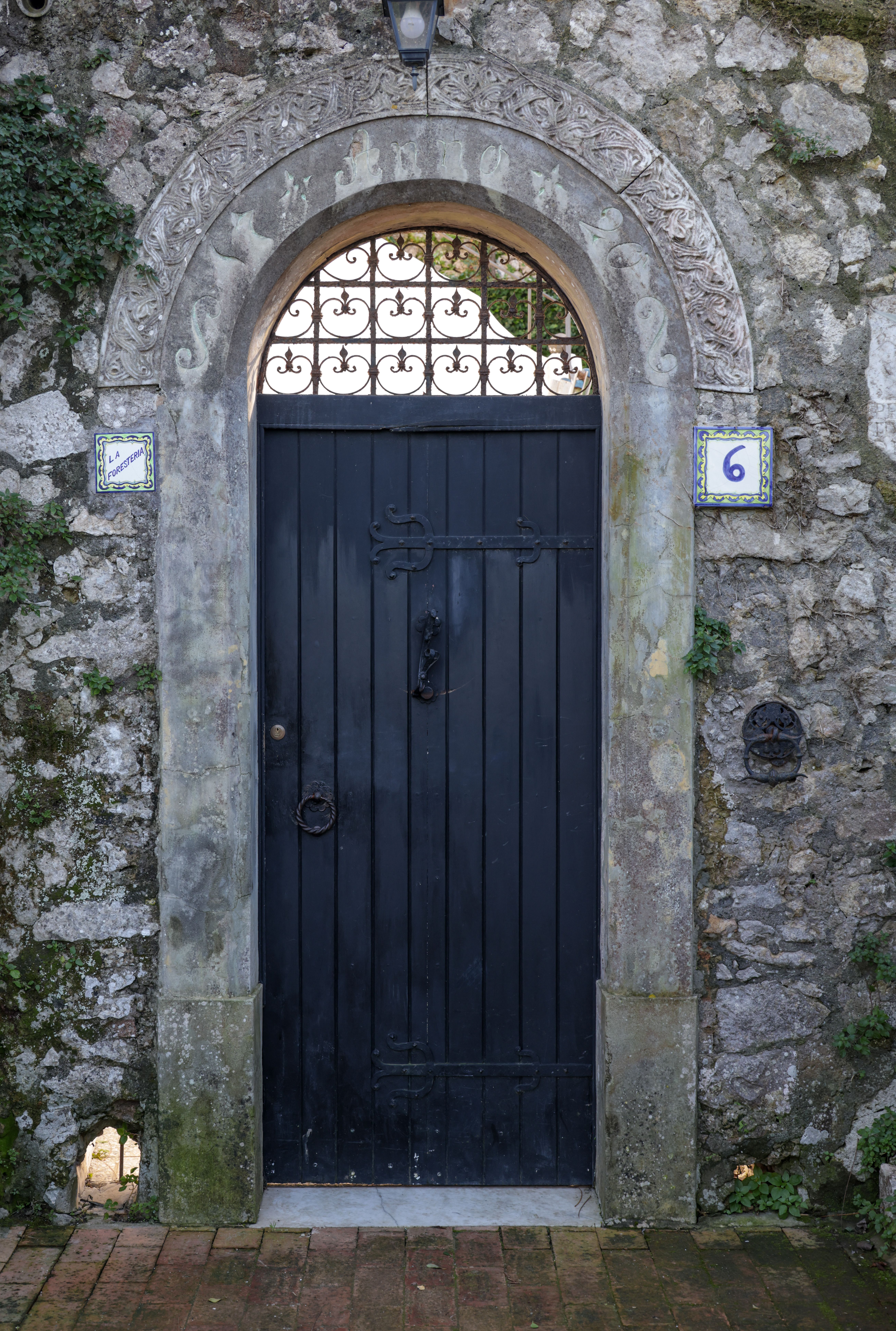 Stone archway entrance with a wooden door in a Mediterranean setting.