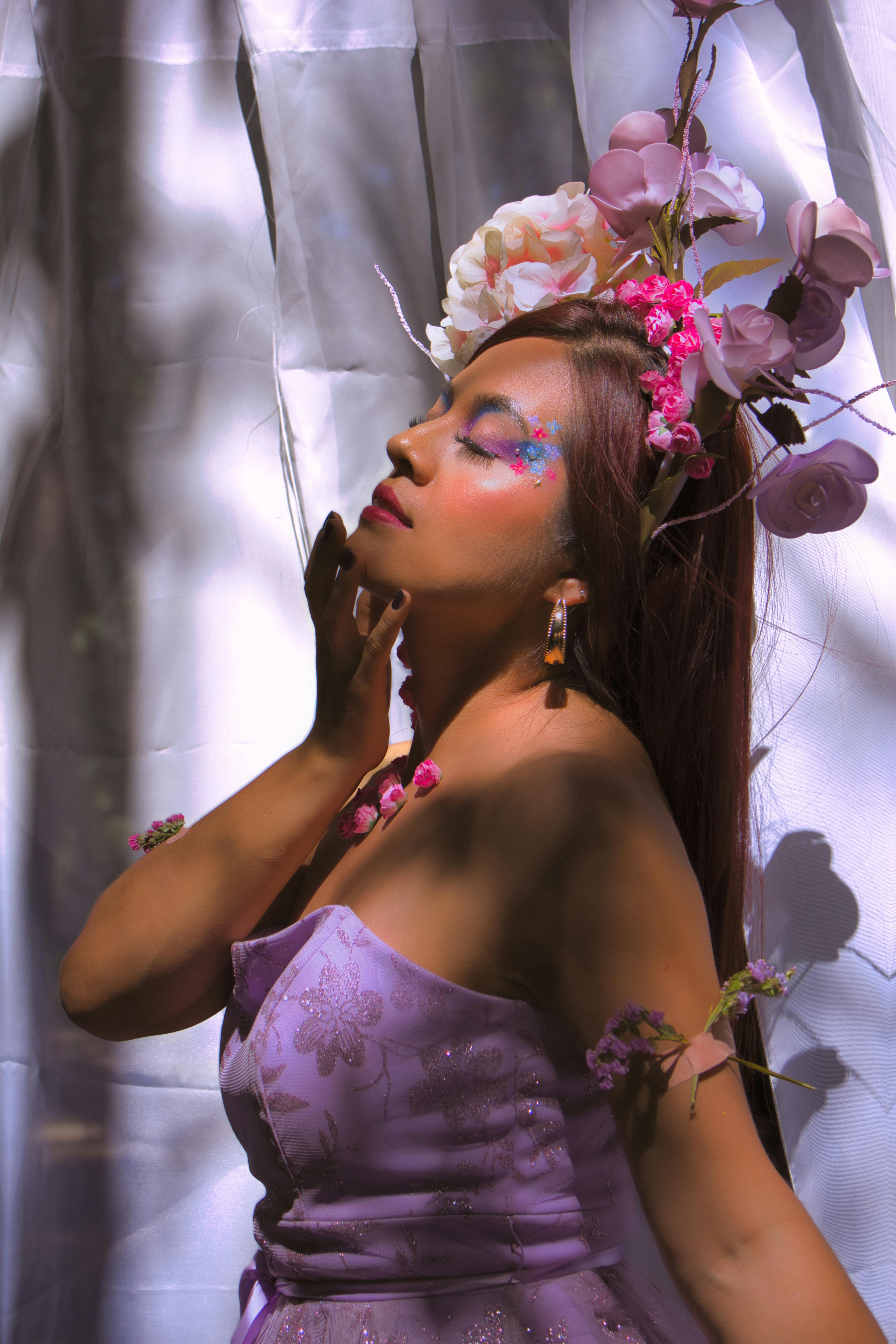 grátis Mulher de vestido roxo e adorno floral na cabeça desfruta de uma iluminação suave, exalando elegância. Foto profissional