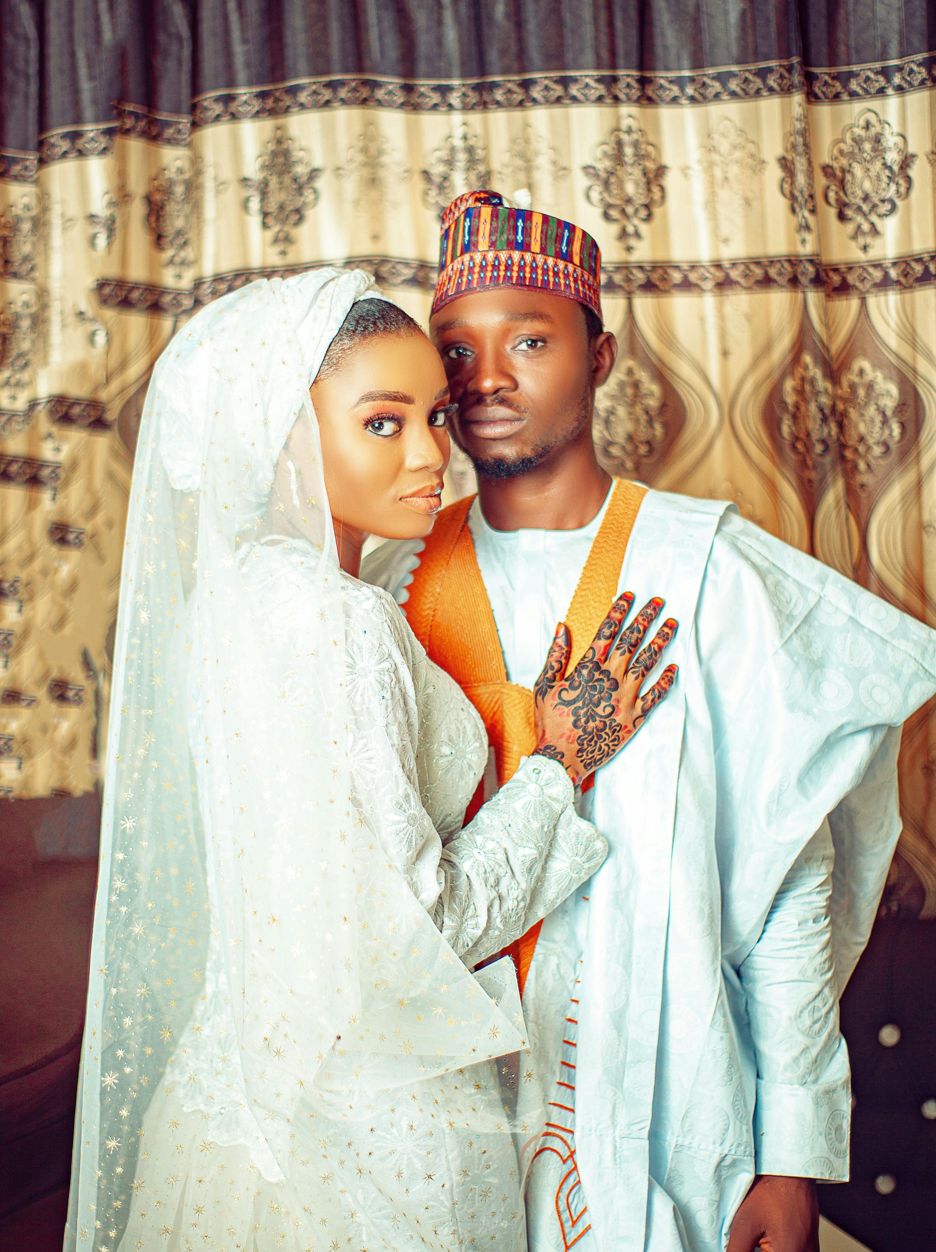 De franc Una parella amb vestit de núvia tradicional africà, abraçant-se a l'interior amb tons càlids. Foto d'estoc