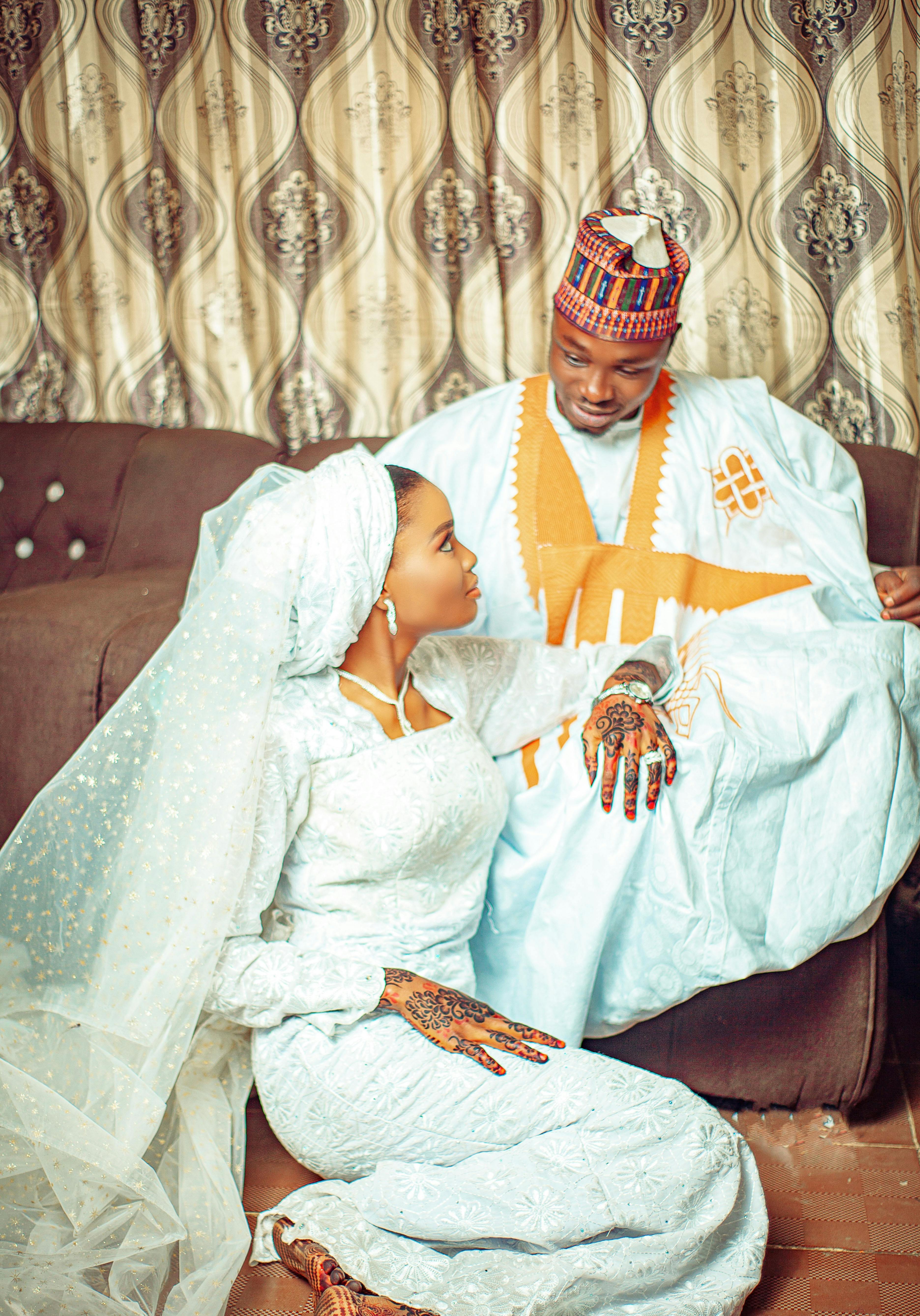 De franc Una parella amb vestit tradicional de núvia nigerià, asseguda a casa, compartint un moment íntim. Foto d'estoc