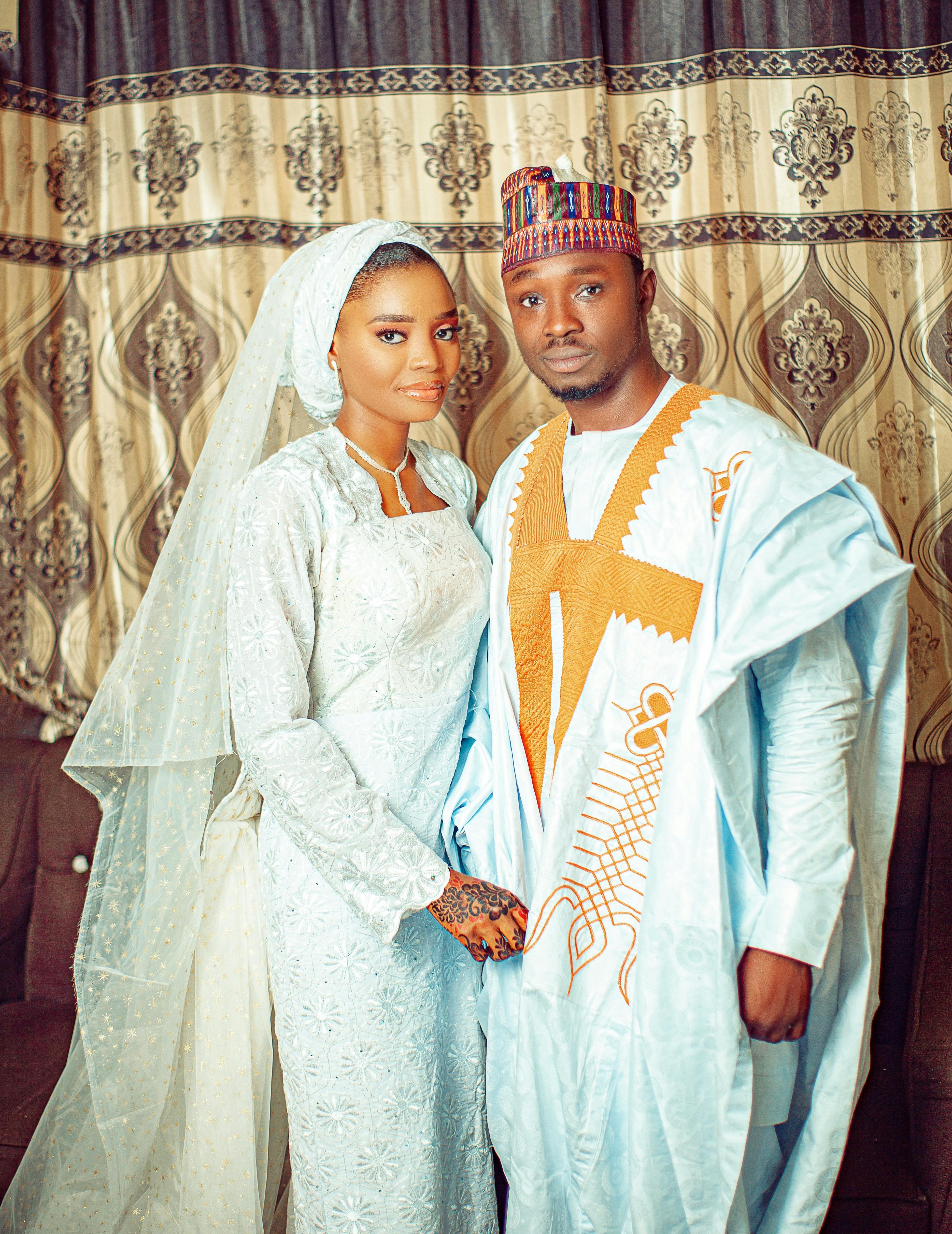 De franc Bonica parella amb vestits de núvia tradicionals, posant elegantment a l'interior. Foto d'estoc