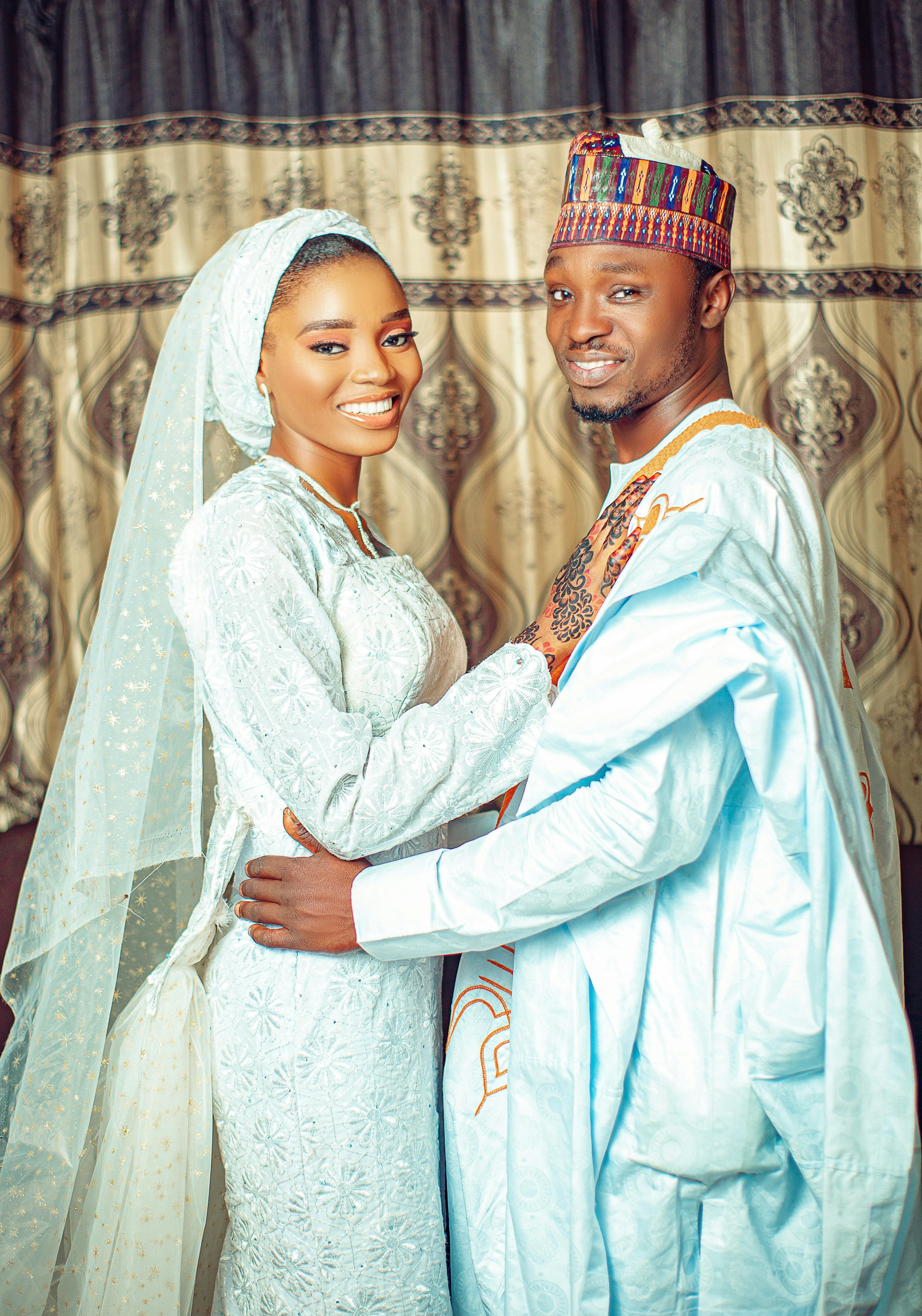 De franc Una parella bonica amb vestit tradicional de casament africà somrient càlidament posant a l'interior. Foto d'estoc