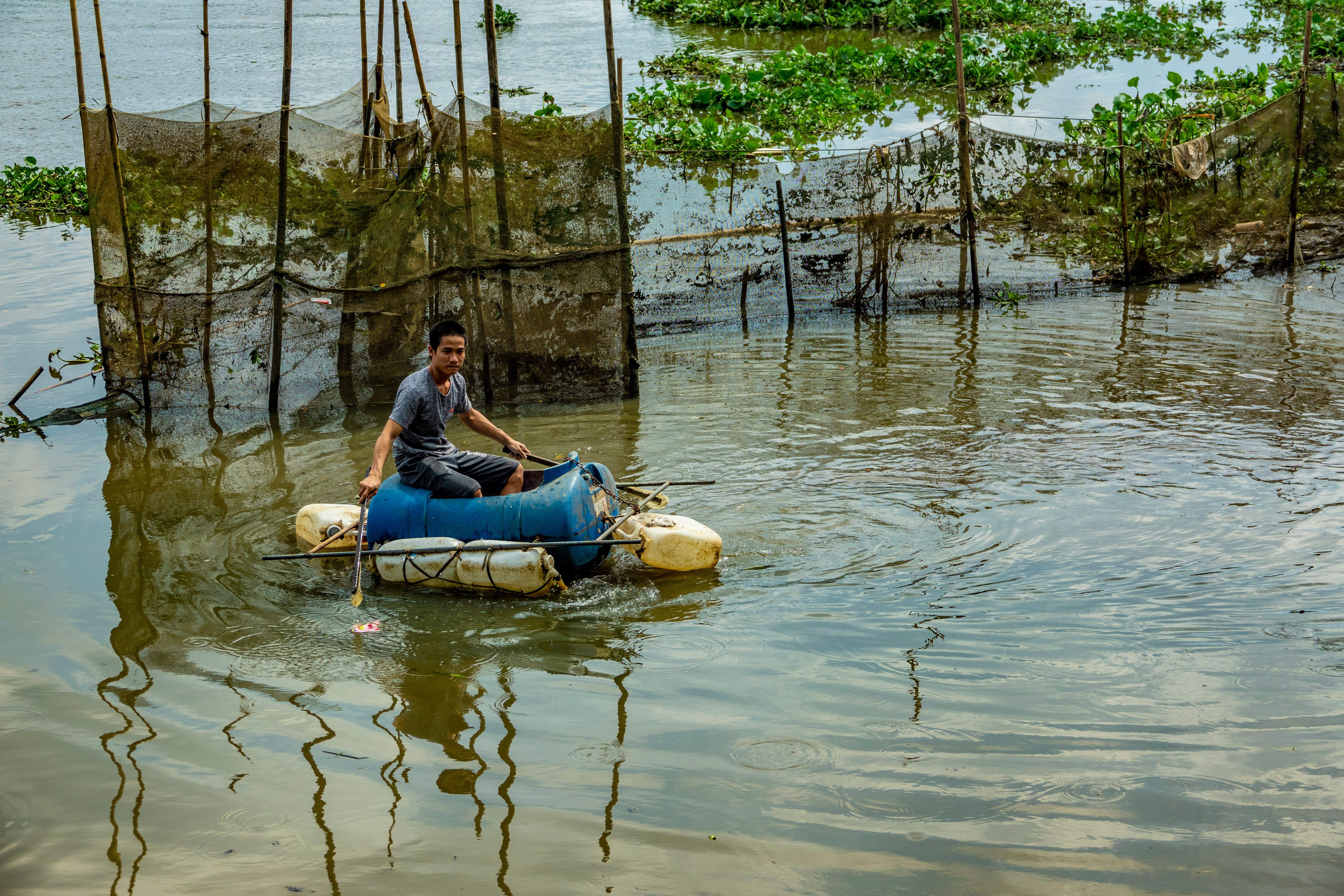 Young Man on Homemade Raft Across Waterway · Free Stock Photo