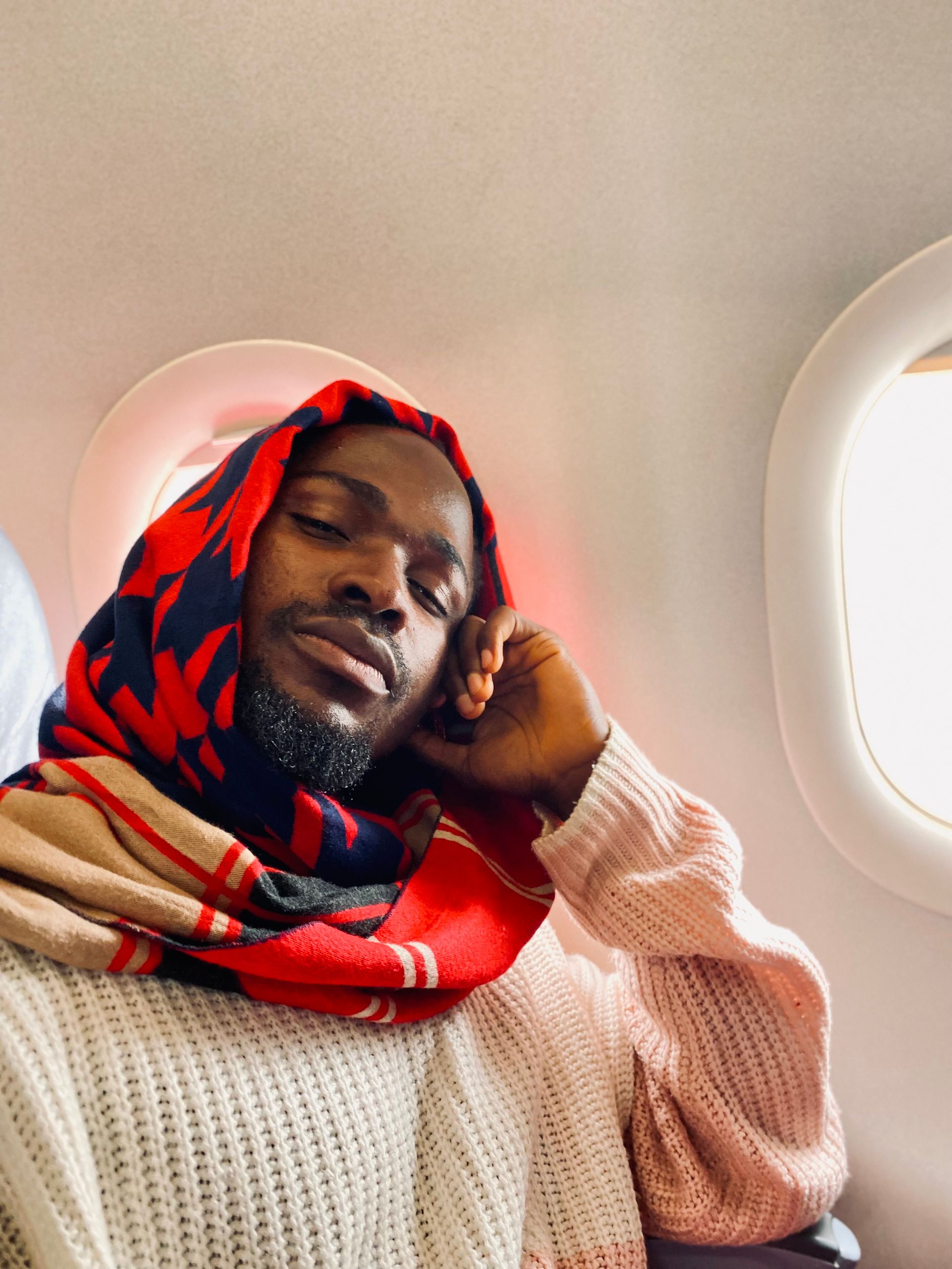 A relaxed traveler looking out of an airplane window seat