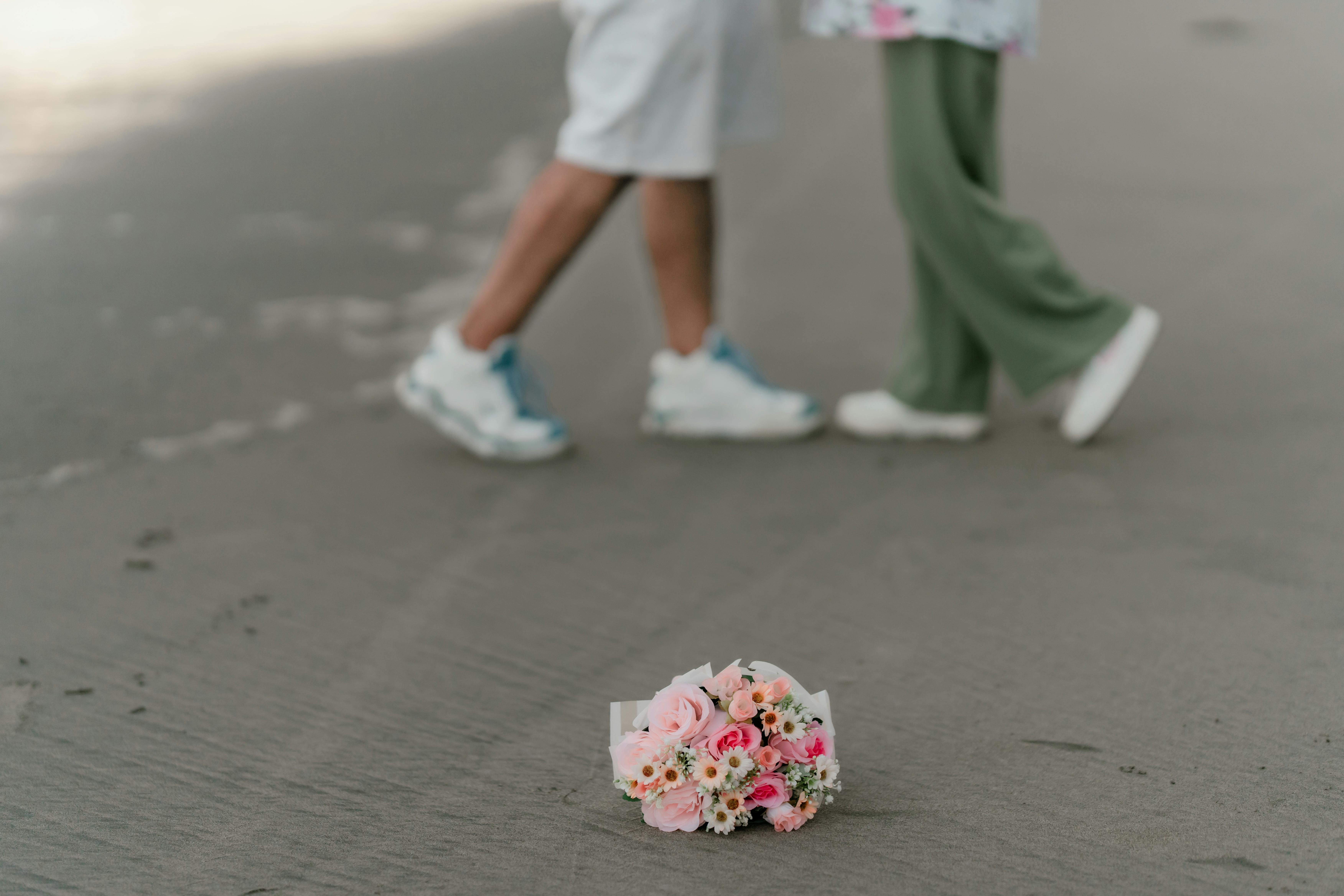 Gratis Et romantisk øjeblik, hvor et par går forbi en smuk blomsterbuket på jorden. Lagerfoto