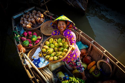 Free A joyful woman selling fresh fruits from her boat on a sunny day at a floating market. Stock Photo