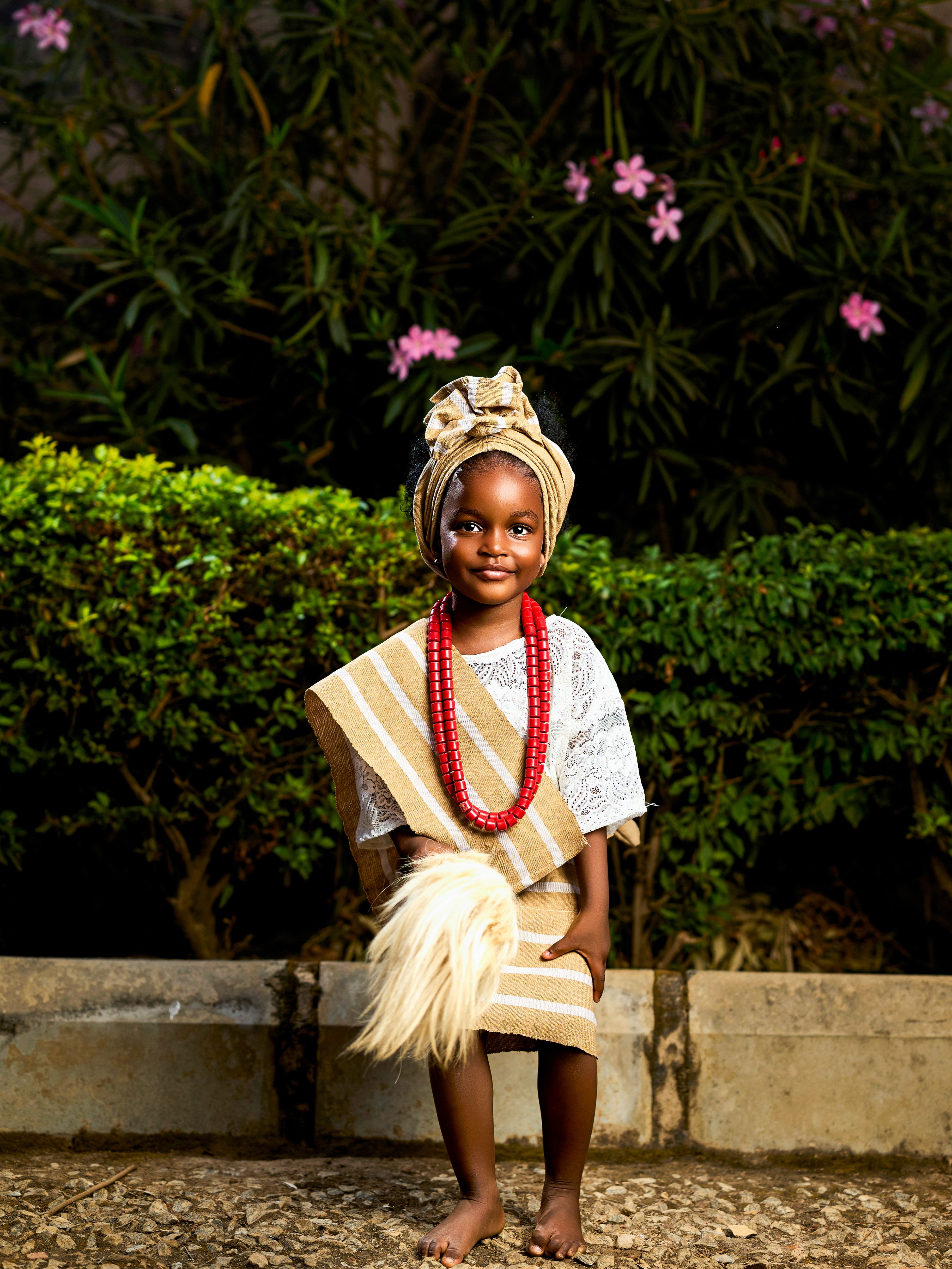 Young African girl in traditional clothing with colorful beads outdoors.