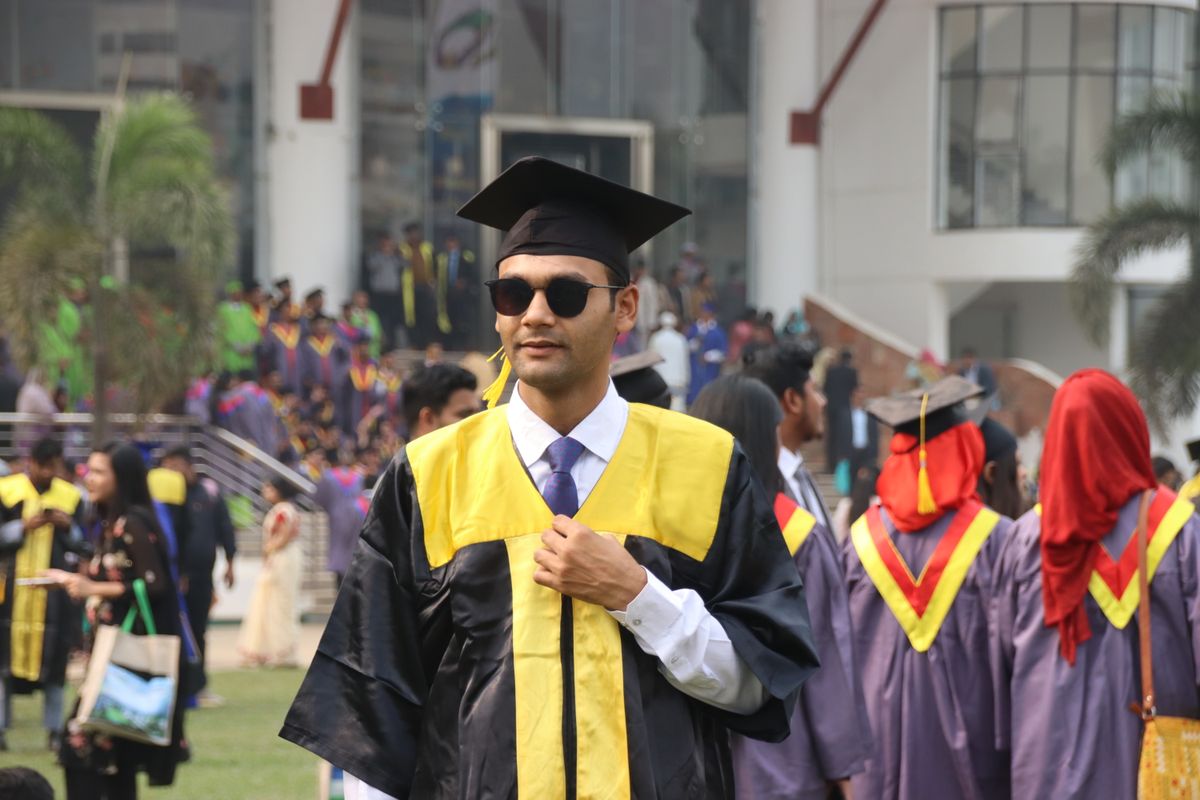 University graduates celebrating at an outdoor commencement ceremony in traditional caps and gowns