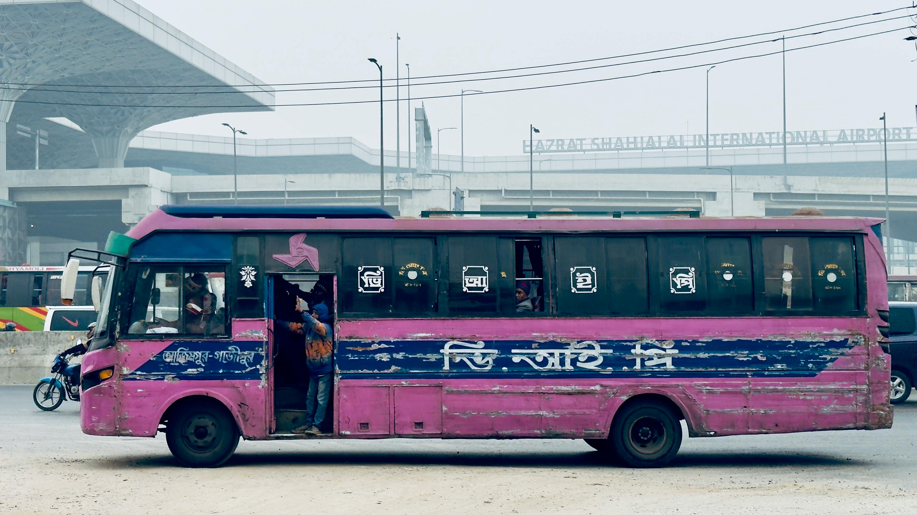 A vibrant pink city bus near Hazrat Shahjalal International Airport, Dhaka.