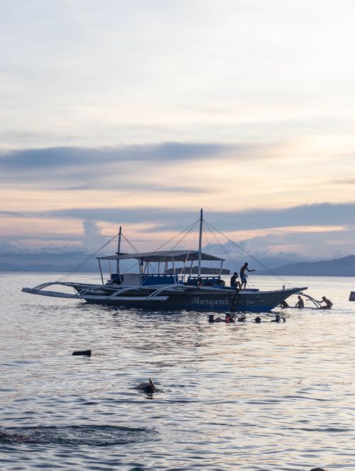 Free A traditional boat and snorkelers enjoying the serene waters of Moalboal, Philippines. Stock Photo