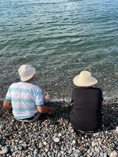 Free Elderly couple sitting by the seaside, enjoying a peaceful day at the pebble beach. Stock Photo