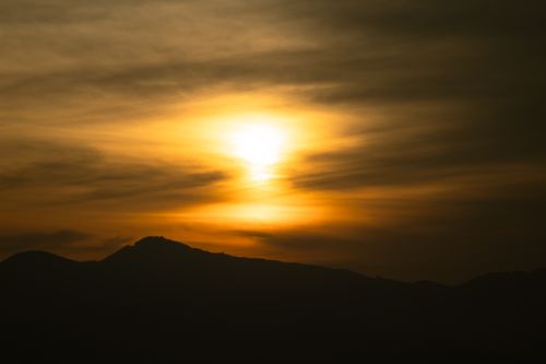 Free A mesmerizing sunset casting golden hues over silhouetted mountains, creating a serene and tranquil atmosphere. Stock Photo