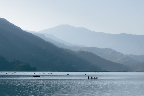 Free Canoes on a peaceful lake surrounded by mountain views at daytime. Stock Photo