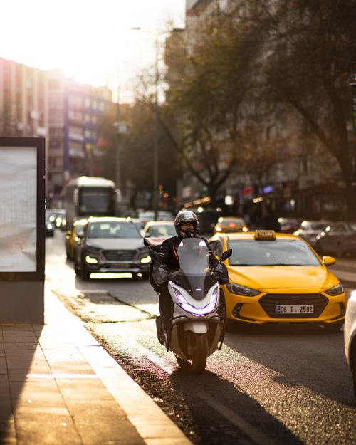 Free Motorcycle and taxi in bustling city street during sunset, capturing urban life. Stock Photo