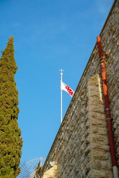 Free A flag atop a stone wall with a clear blue sky background. Stock Photo