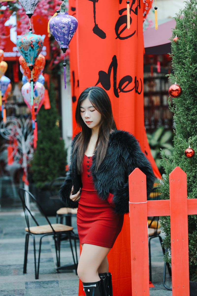 woman in black coat with faux fur collar over red dress