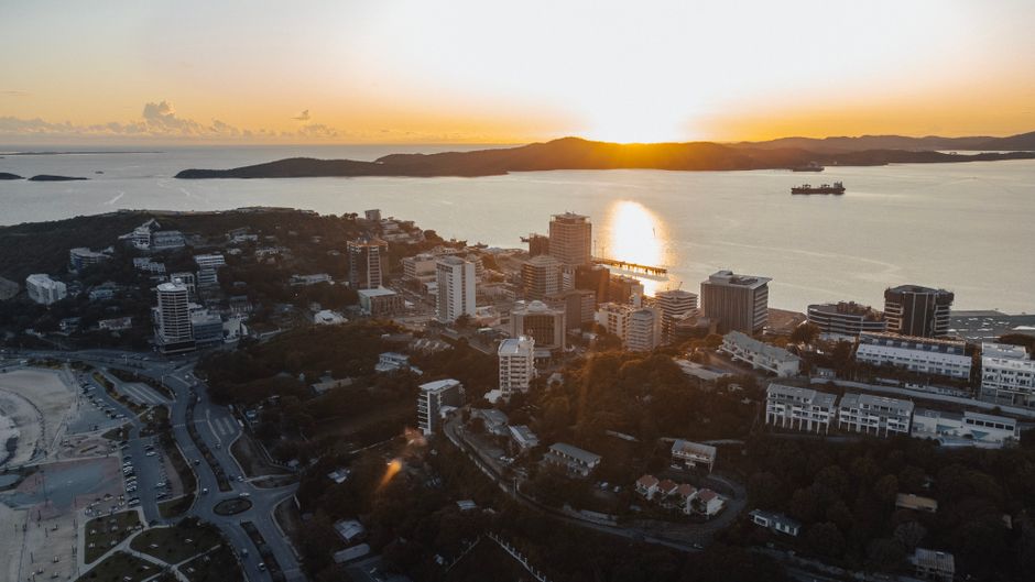 Stunning aerial view of Port Moresby skyline at sunset, featuring coastal beauty and urban landscape.
