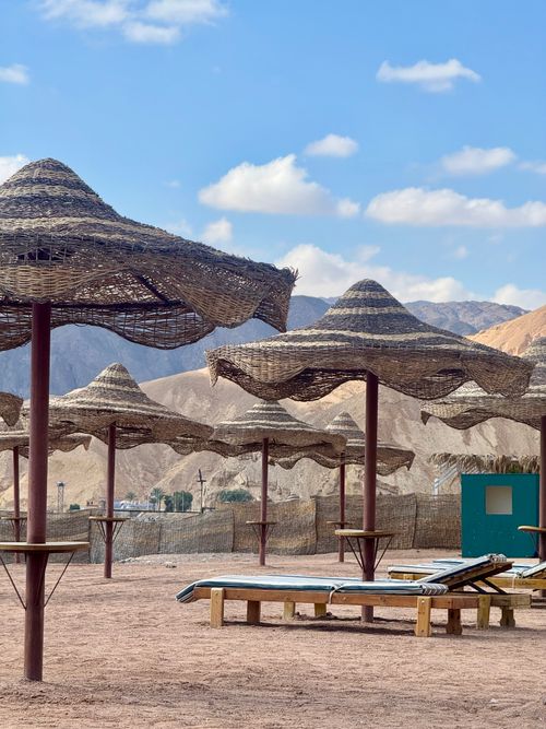 Free Serene beach with wicker umbrellas in Sharm El Sheikh, Egypt against a mountain backdrop. Stock Photo