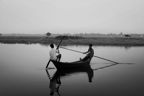 Free Two men rowing a boat on a serene river in Cumilla, Bangladesh, captured in black and white. Stock Photo