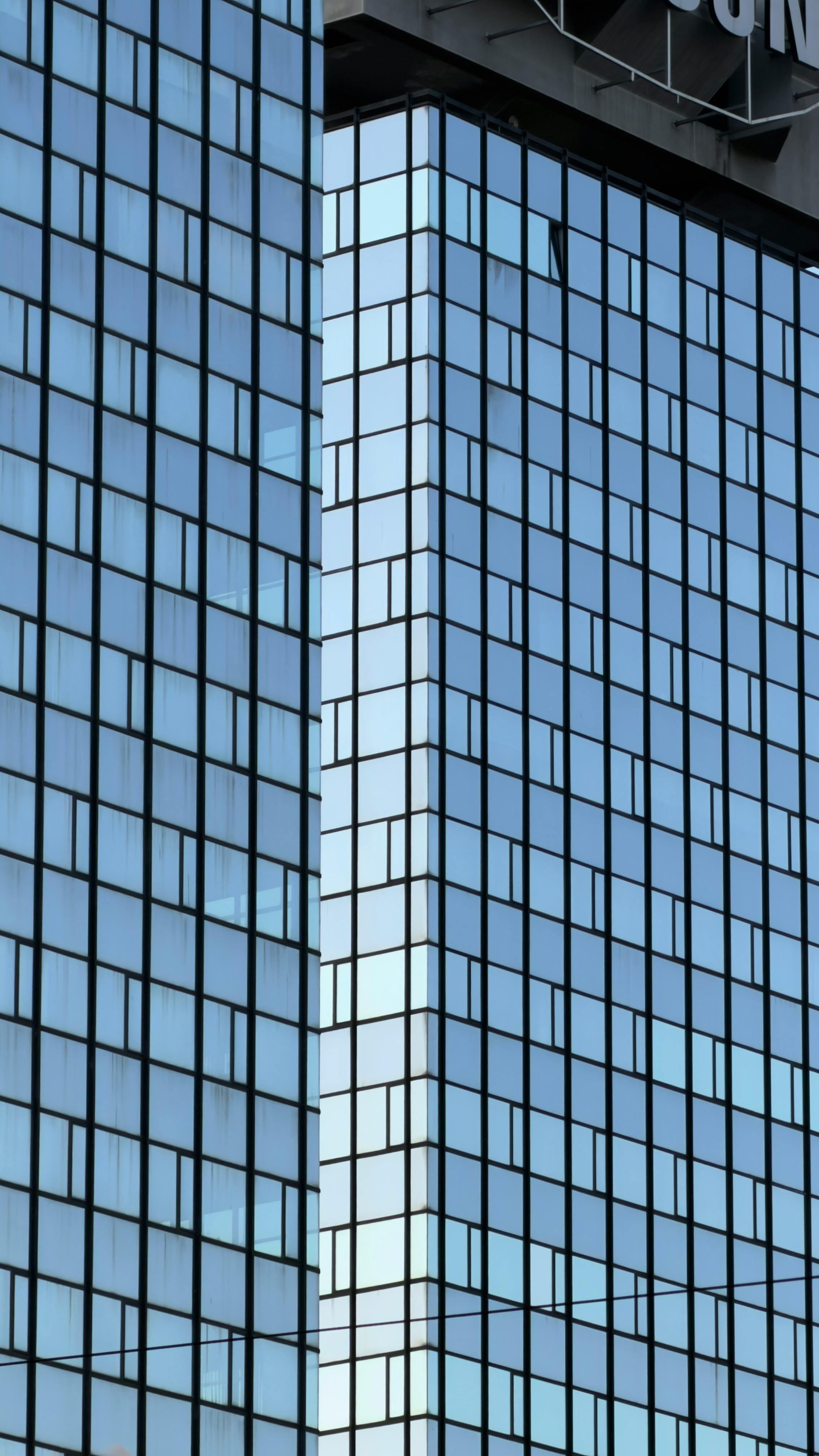 ingyenes Közeli kép egy modern üvegfelhőkarcoló külsejéről, kék fényvisszaverő ablakokkal. Stockfotó