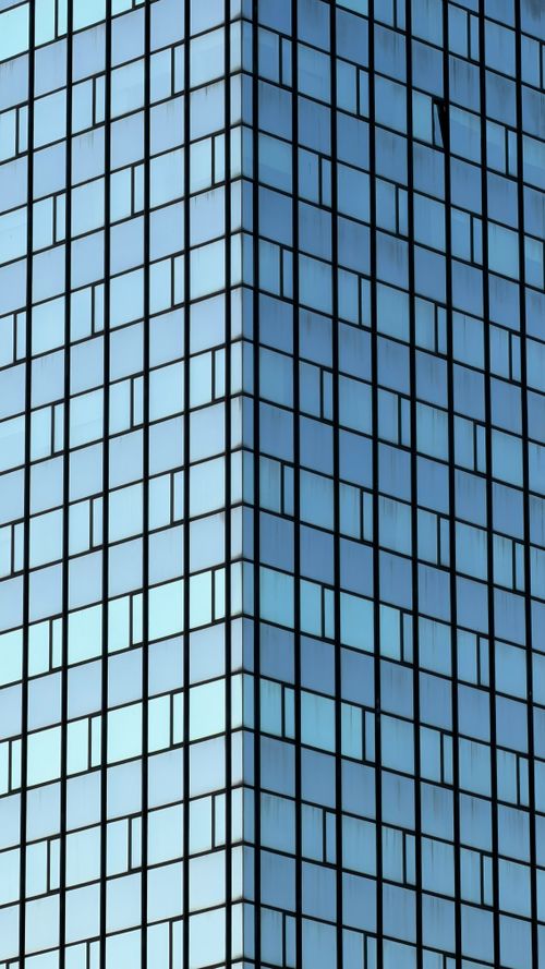 Free Close-up of a modern glass skyscraper facade with geometric patterns. Stock Photo