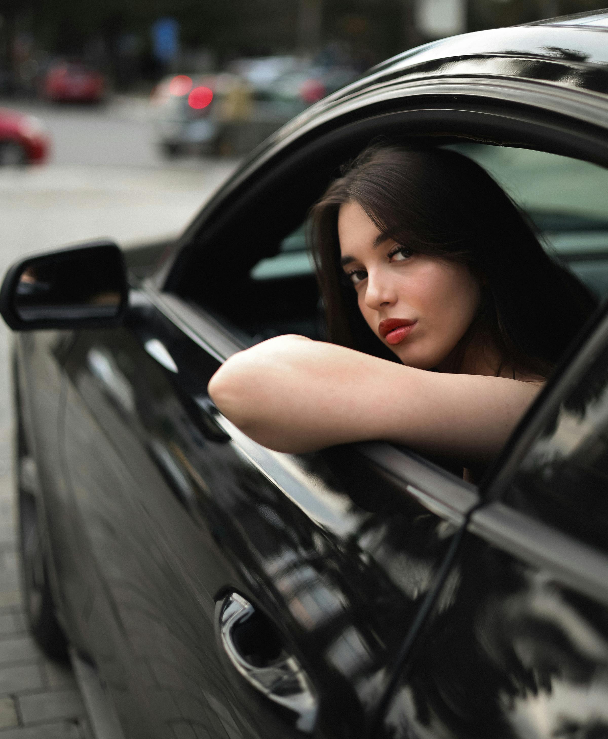 Gratis Mujer elegante mirando por la ventana de un automóvil por la noche, capturando las luces de la ciudad y los tonos oscuros. Foto de stock