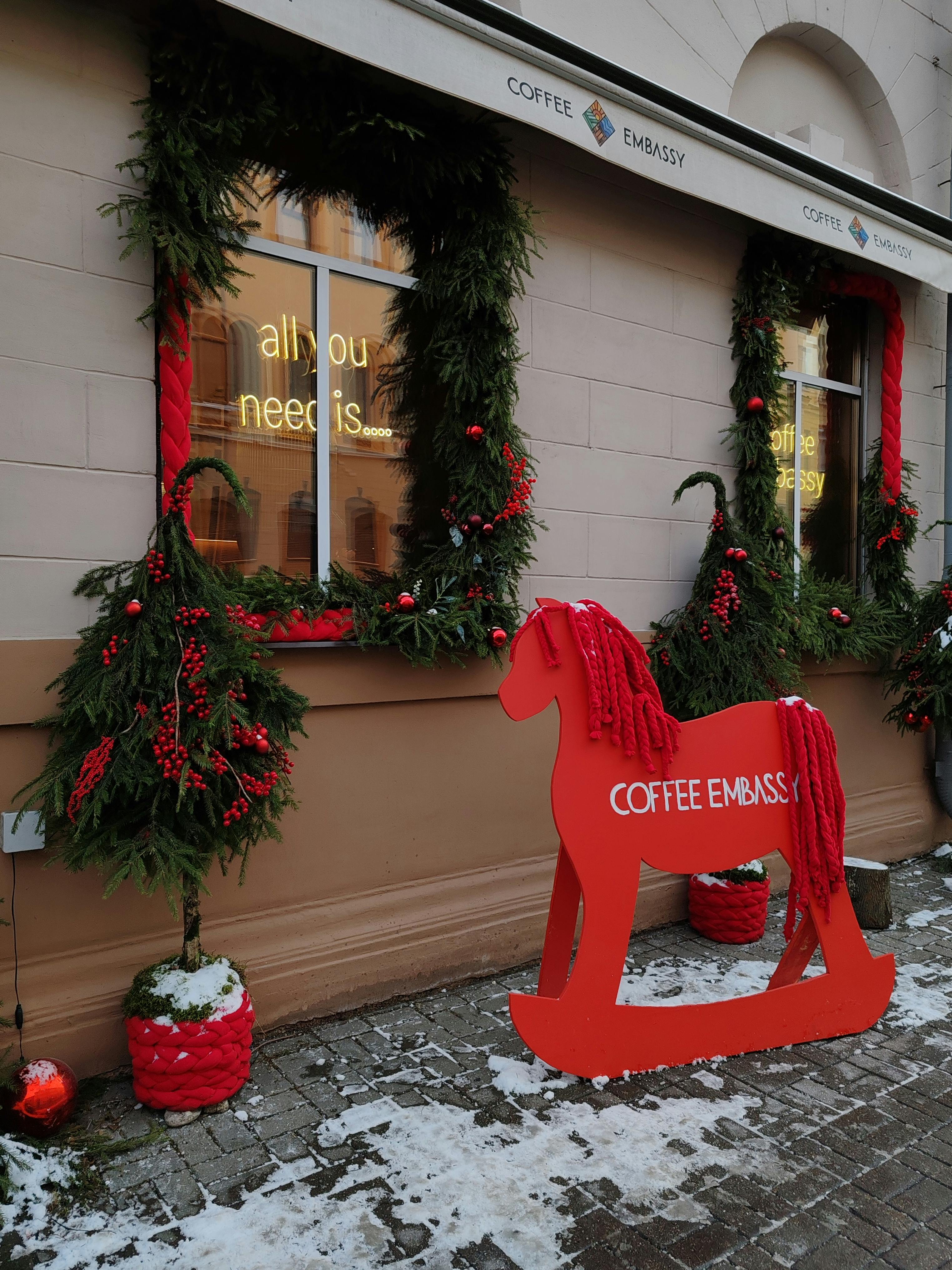 Festive storefront display with red decor and greenery at Coffee Embassy in winter.
