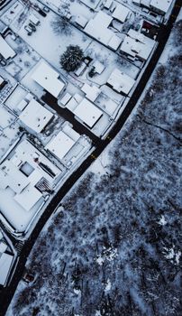 A stunning aerial view of a snow-covered residential area juxtaposed with a forest.