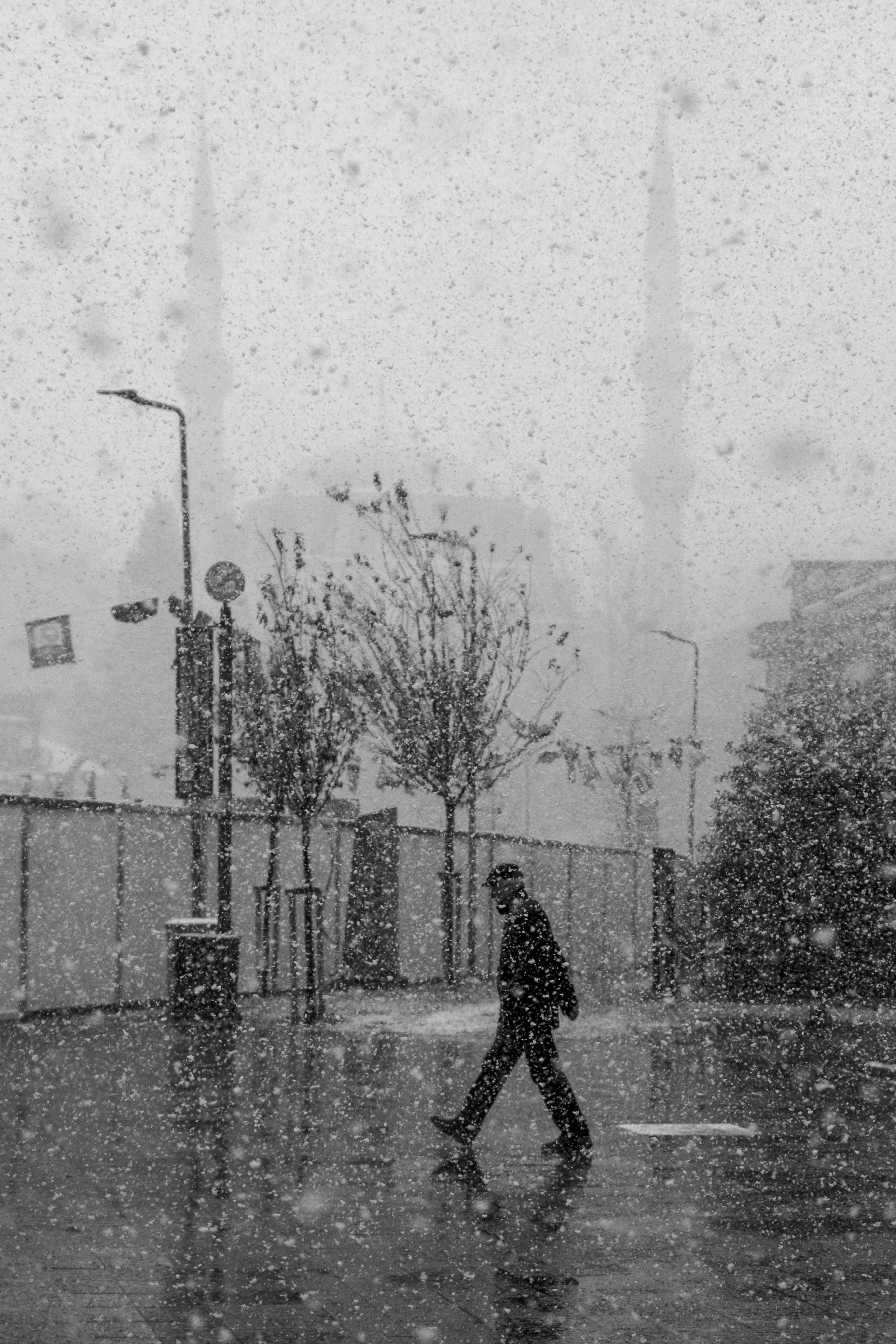 Person walks in snowy cityscape, creating a serene black and white scene.