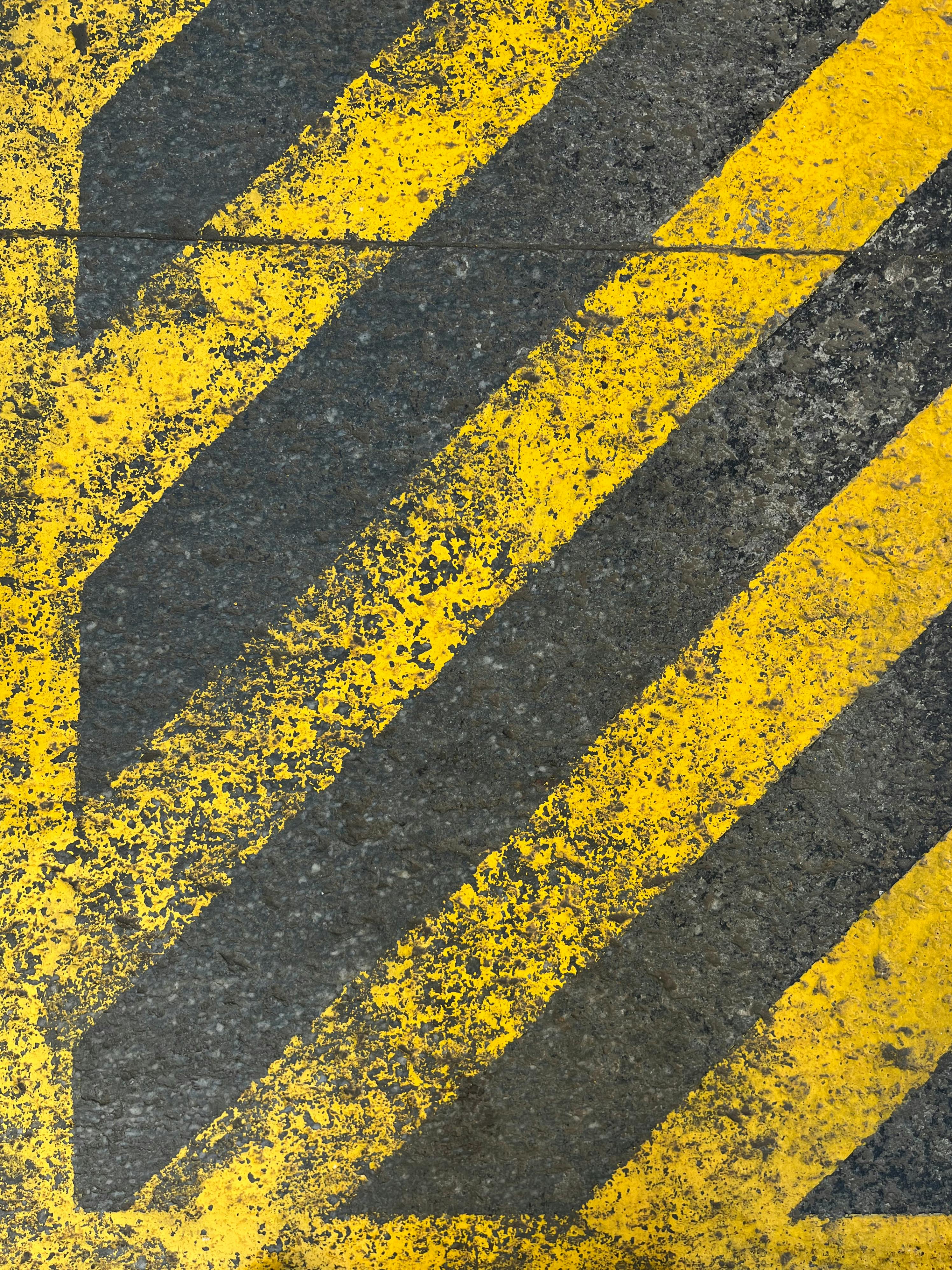Gratuit Gros plan sur des marquages routiers diagonaux jaunes et noirs usés sur la chaussée, montrant leur texture. Photos