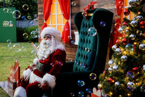 Free Santa Claus sits in a cozy holiday setting with bubbles, adding magic to Christmas festivities. Stock Photo