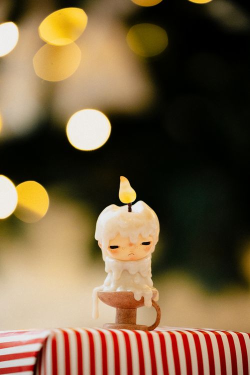 Free Adorable candle in front of a festive bokeh background, adding warmth to any holiday setting. Stock Photo