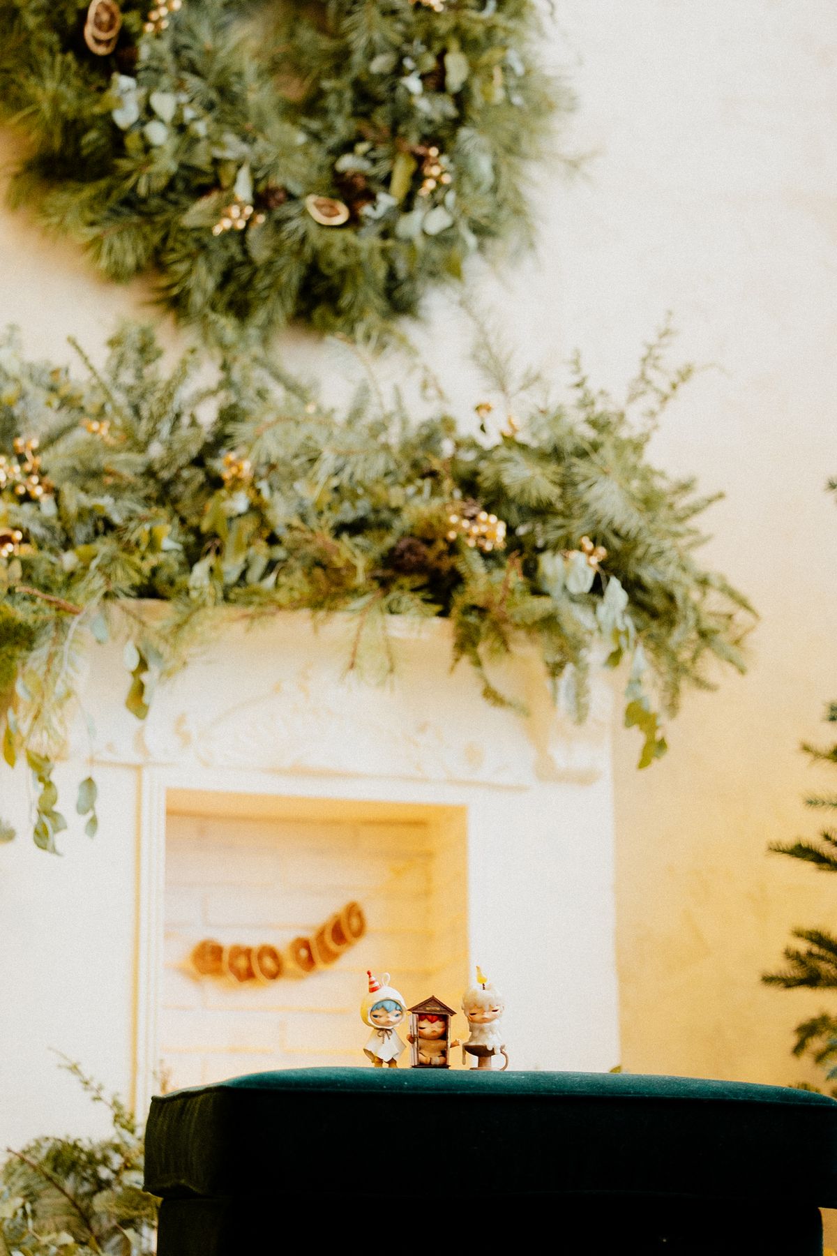 White fireplace mantel covered in a full, lush pine garland with a matching wreath above it