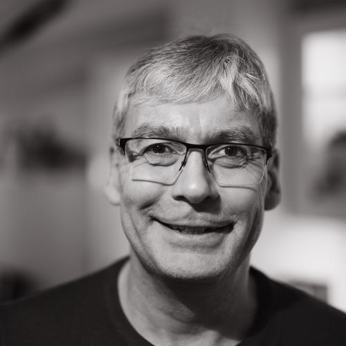 Free Close-up black and white portrait of a smiling man wearing glasses indoors. Stock Photo